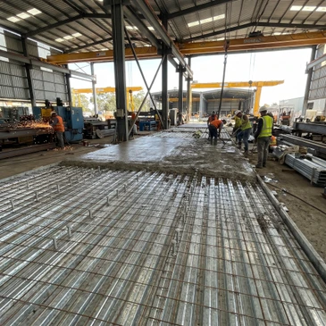 Chantier de construction extérieur avec ouvriers coulant du béton frais sur ferraillage